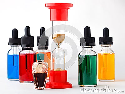 Glass bottles filled colored liquid with dropper and hourglass on white background. Stock Photo
