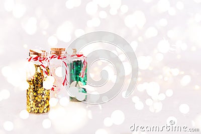 Glass bottles with glitter confetti on white background with bokeh lights. Holiday Christmas and New Year background Stock Photo