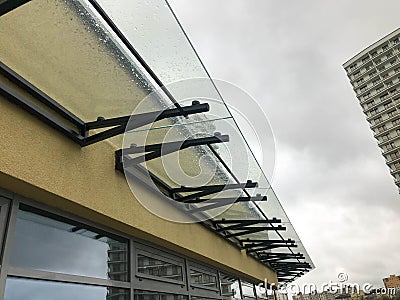 Glass canopy for collecting rain drops. the roof of the shopping center on black fortifications to protect the building Stock Photo