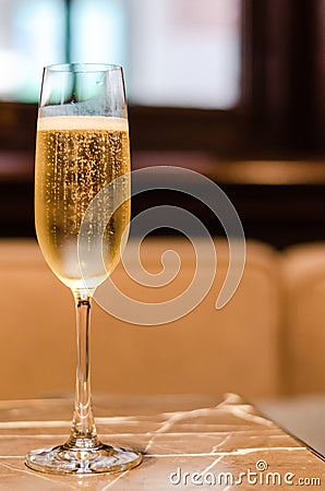 A glass of Champagne puts on marble table in restaurant for celebration with blurred background Stock Photo