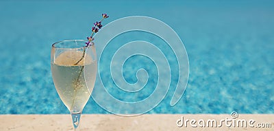 Glass of champagne with sprig of lavender against poolside at resort hotel during vacation Stock Photo