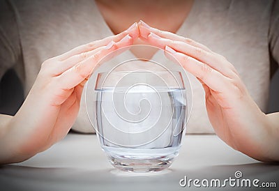 A glass of clean mineral water covered by woman's hands. Environment protection Stock Photo