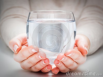 A glass of clean mineral water in woman's hands. Environment protection, healthy drink. Stock Photo