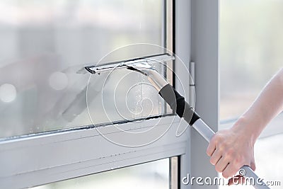 Glass cleaner using a squeegee to wash a window. Stock Photo