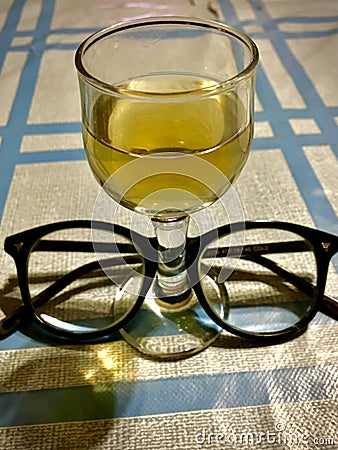 a glass of cognac and optical glasses on a steel checkered tablecloth Stock Photo