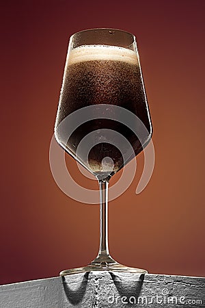 Glass of cold frothy dark beer on an old wooden table Stock Photo