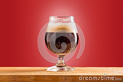 Glass of cold frothy dark beer on an old wooden table Stock Photo
