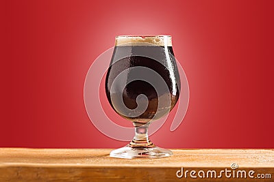 Glass of cold frothy dark beer on an old wooden table Stock Photo