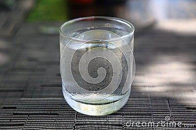 Glass of cold water on grey brown background on a warm summer day. Temperature contrast. Stock Photo