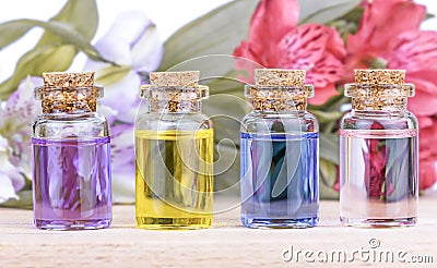 Glass colorful bottles aroma oil and flowers on wooden table Stock Photo