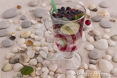 Glass with a cooling drink of berries and ice. Misted glass. Air bubbles on glass. A slice of lemon on a plate on the background Stock Photo