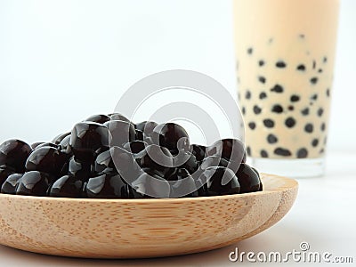 A glass cup of pearl milk tea also called bubble tea and a plate of tapioca ball on white background. Stock Photo