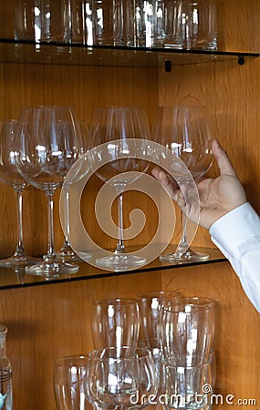 Glass cups on a glass shelving with an appearing hand Stock Photo