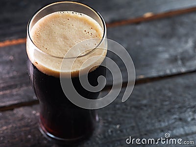 A glass of dark craft beer porter on a wooden table Stock Photo