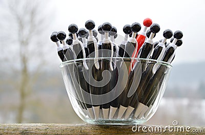 A glass dish with black globule ballpoint pens with a red one Stock Photo