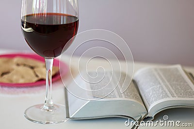 A glass of dry red wine and broken unleavened bread lie on a plate. To celebrate the Lord`s Supper. Nearby lies the Bible Stock Photo