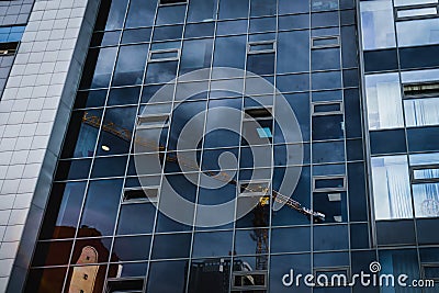 Glass facade of office building with construction crane reflection Stock Photo