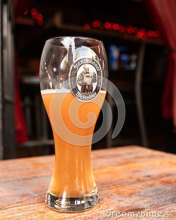 Glass of Franziskanker Weissbier Beer on table at bar. Editorial Stock Photo