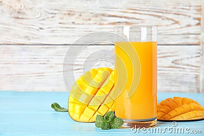 Glass with fresh mango juice and tasty fruits on wooden table Stock Photo