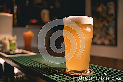 Glass of frothy wheat unfiltered beer on bar counter in pub Stock Photo