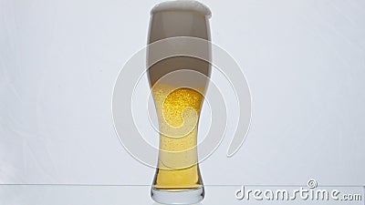 Glass full foamy beer overflowing in super slow motion close up. Bubbling foam. Stock Photo