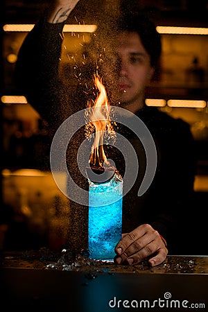 glass full of ice and drink with fire and hand of bartender accurate sprinkle powder on it Stock Photo
