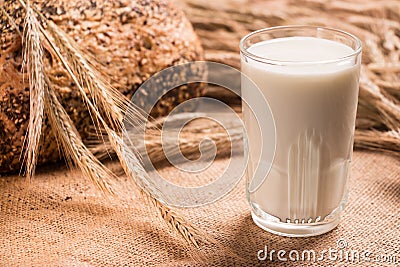 Glass glass of milk, a loaf of bread, wheat spikelets . Stock Photo