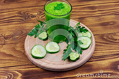 Glass of green detox smoothie of cucumber and parsley on wooden table Stock Photo