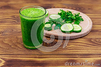 Glass of green detox smoothie of cucumber and parsley on wooden table Stock Photo