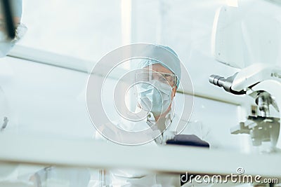 through the glass. group of scientists in protective masks work in the laboratory. Stock Photo