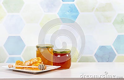 Glass honey jars with different color honey inside, lot of copy space on blue. Stock Photo
