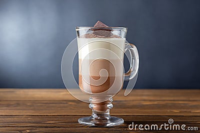 Glass of hot chocolate of three layered drink on wooden table. Stock Photo