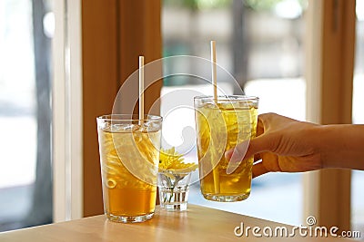 Glass of iced bael fruit herbal drink and Chinese chrysanthemum tea with ice on wooden table. Stock Photo