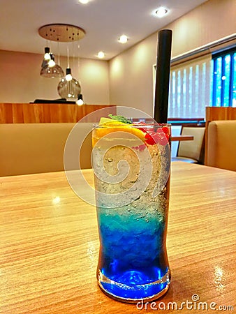 Glass of iced blue lime soda with straw on wooden table Stock Photo