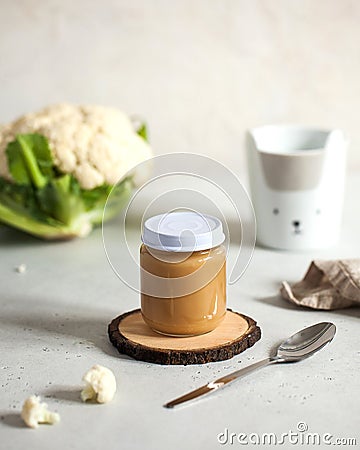 glass jar with baby food cauliflower smoothie with a spoon with fresh cauliflower. Layout Baby food concept. Stock Photo