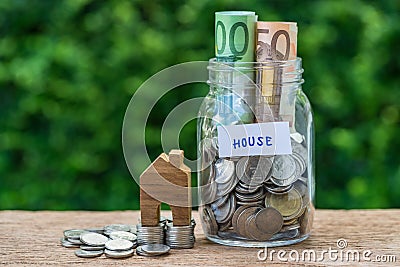 glass jar bottle labeled as house with full of coins and miniature house on stack of coins as home, property or mortgage Stock Photo