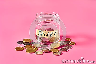 Glass jar with coins and inscription salary lies on pink Stock Photo