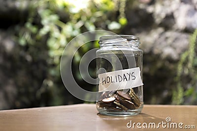 A glass jar with coins inside and a `vacaciones` tag on a wooden. Un bote de cristal con monedas dentro, tiene una etiqueta que po Stock Photo