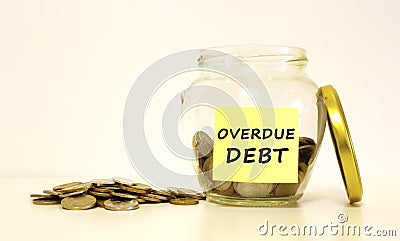 Glass jar with coins for savings. The inscription on the note paper Overdue debt. Financial concept Stock Photo