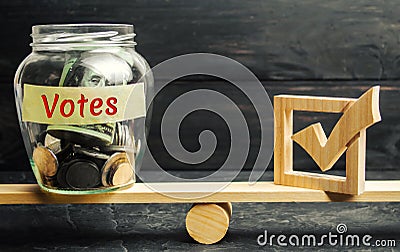 Glass jar with coins and the words `Votes` and a checkbox on the scales. Concept of voting for money. Bribing voters. Corruption i Stock Photo