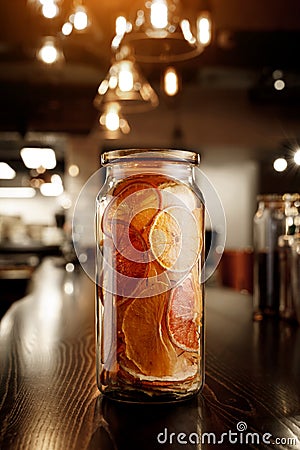 Glass jar with dried citruses on a wooden bar counter Stock Photo