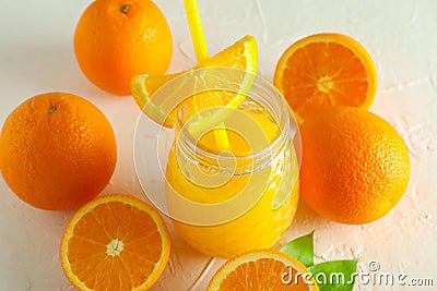 Glass jar with fresh orange juice and tubule, oranges on white background Stock Photo
