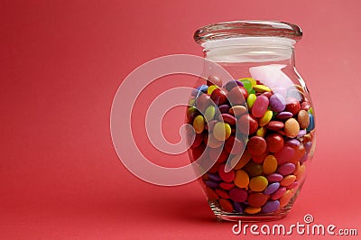 Glass Jar full of bright colorful lollies and candy with closed lid with copy space. Stock Photo