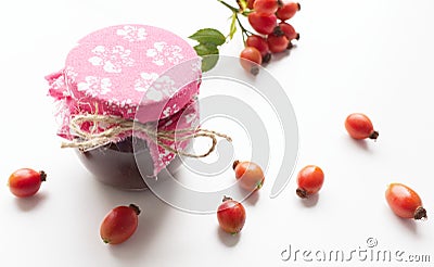 Glass jar of homemade rosehip jam with fresh juicy fruits in the form of ingredients, isolated on white background Stock Photo