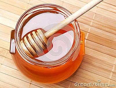 Glass jar of honey with wooden drizzler Stock Photo