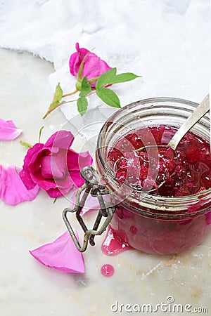 Glass jar and little spoon with tea rose petal jam on light marble background. Copy space for text. Stock Photo