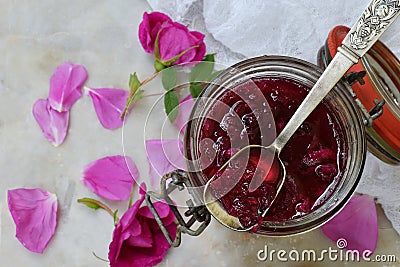 Glass jar and little spoon with tea rose petal jam on light marble background. Copy space for text. Stock Photo