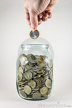 Glass jar with money on a white background. Hand with a coin Stock Photo