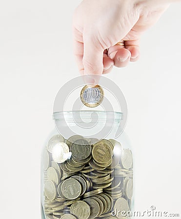 Glass jar with money on a white background. Hand with a coin Stock Photo