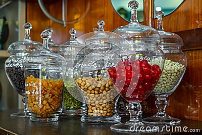 Glass jars with candied cherries, coffee beans, candied orange, hazelnuts, pistachio and white chocolate Stock Photo